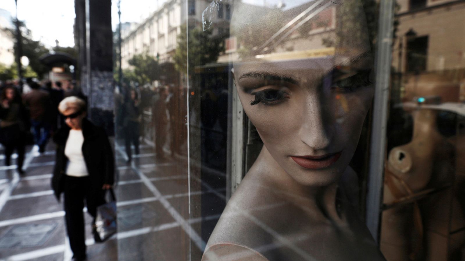 Una mujer camina junto a una tienda cerrada en Atenas, Grecia