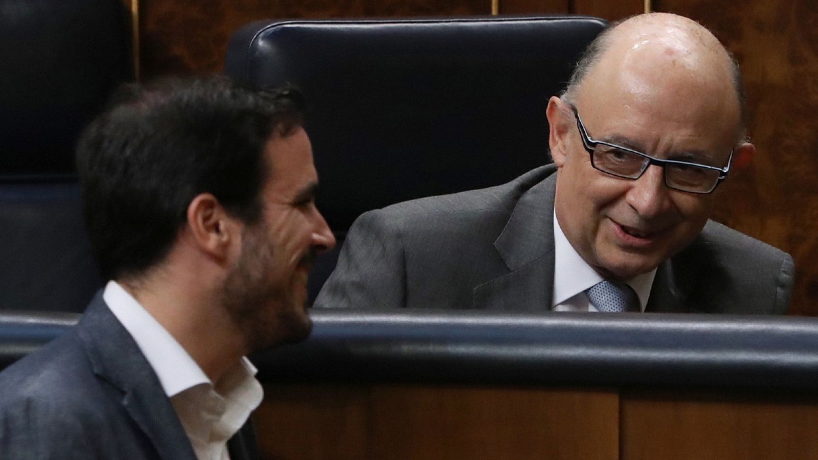 El ministro de Hacienda en funciones, Cristóbal Montoro, conversa con el diputado de Unidos Podemos Alberto Garzón, al inicio del pleno en el Congreso de los Diputados