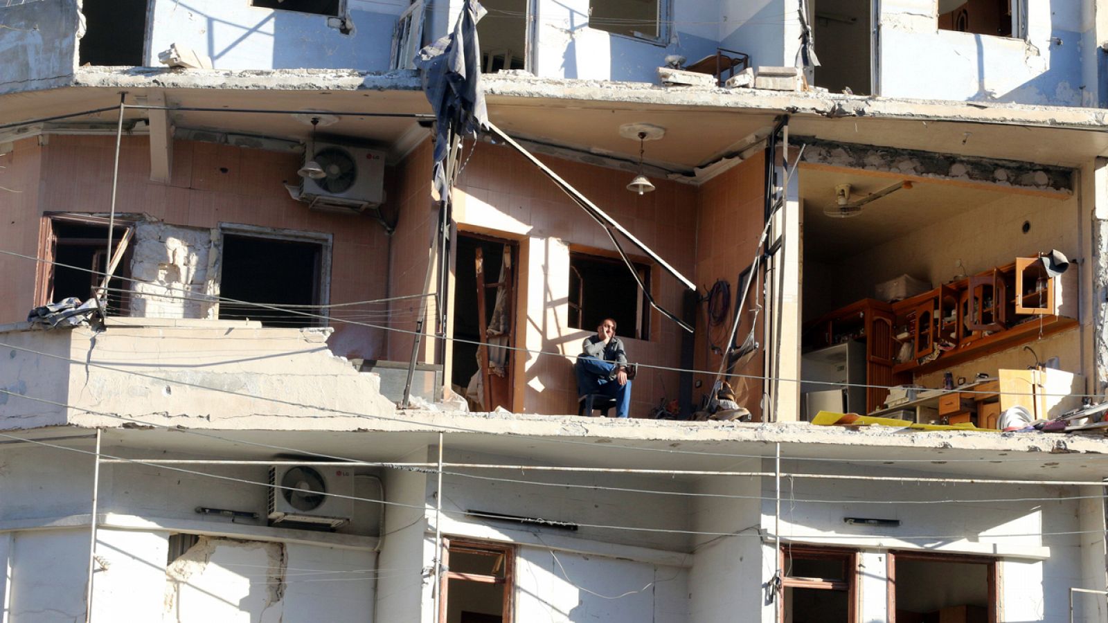 Un hombre aguarda en el interior de su vivienda destruida en el barrio al-Sukkari de Alepo