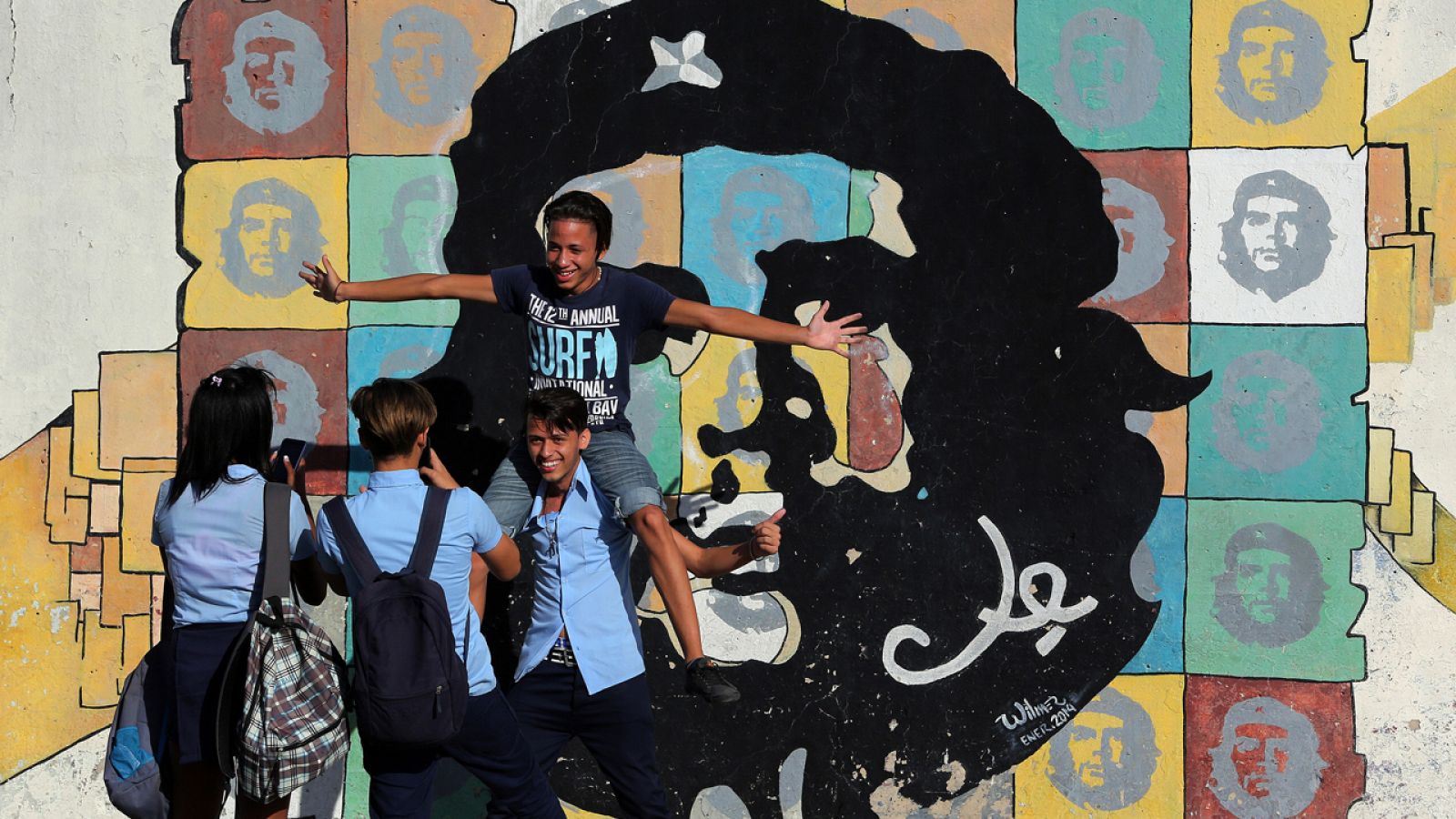 Varios jóvenes posan junto a una imagen del Che Guevara, en La Habana