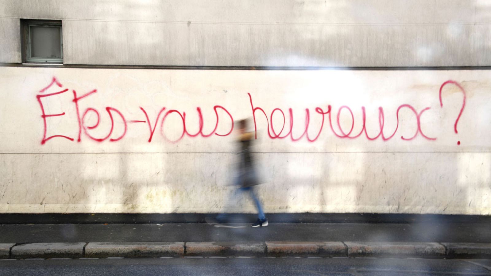 Una desempleada pasa por delante de un grafiti en Rennes