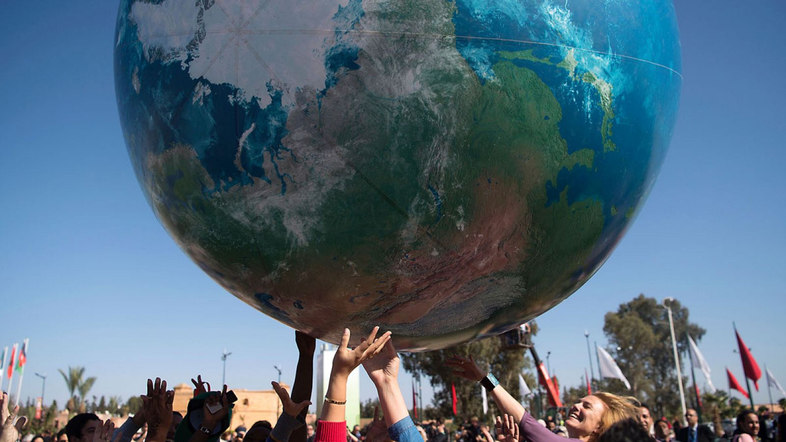 Miembros de las delegaciones internacionales juegan con una gran bola del mundo en el exterior del edificio donde se celebra la COP22 en Marrakech.