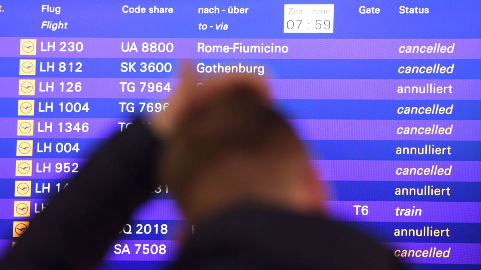 Un hombre observa el panel de información con los vuelos cancelados de Lufthansa en Fráncfort