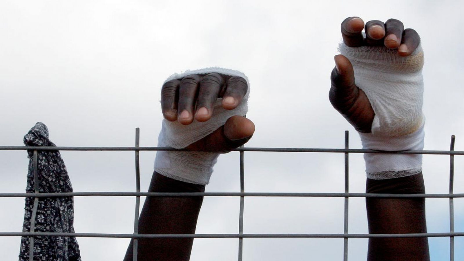Un imigrante trata de superar la valla de entrada a Melilla con las manos protegidas para evitar cortes