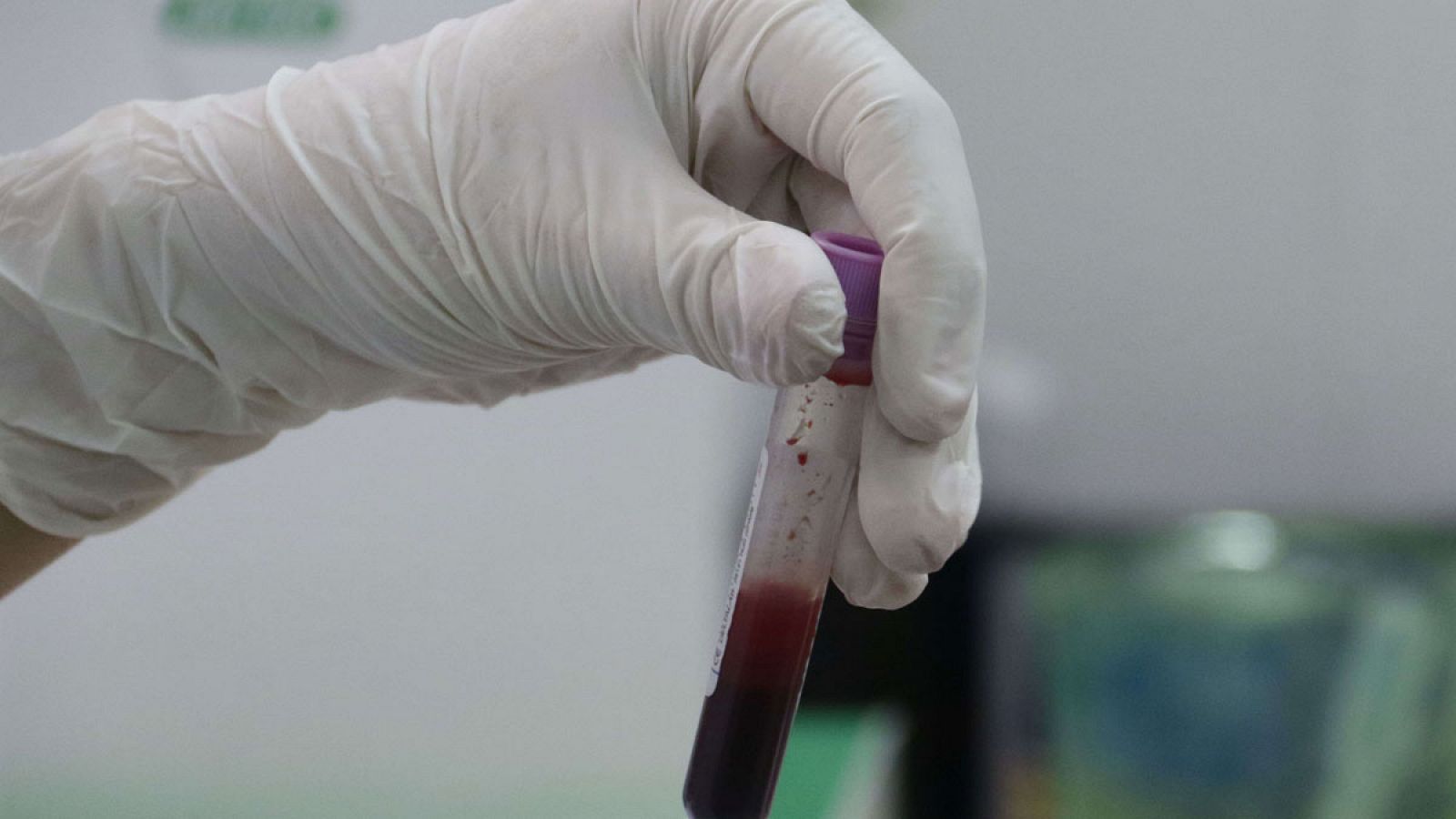 Un experto sostiene un tubo con una muestra de sangre en un laboratorio.