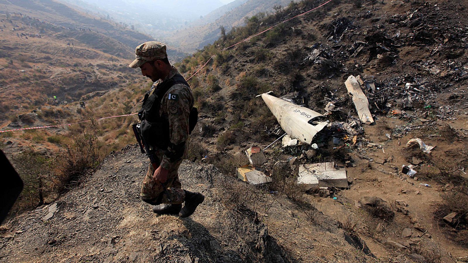 Un soldado paquistaní camina entre los restos del avión siiniestrado cerca de en el norte de Pakistán.