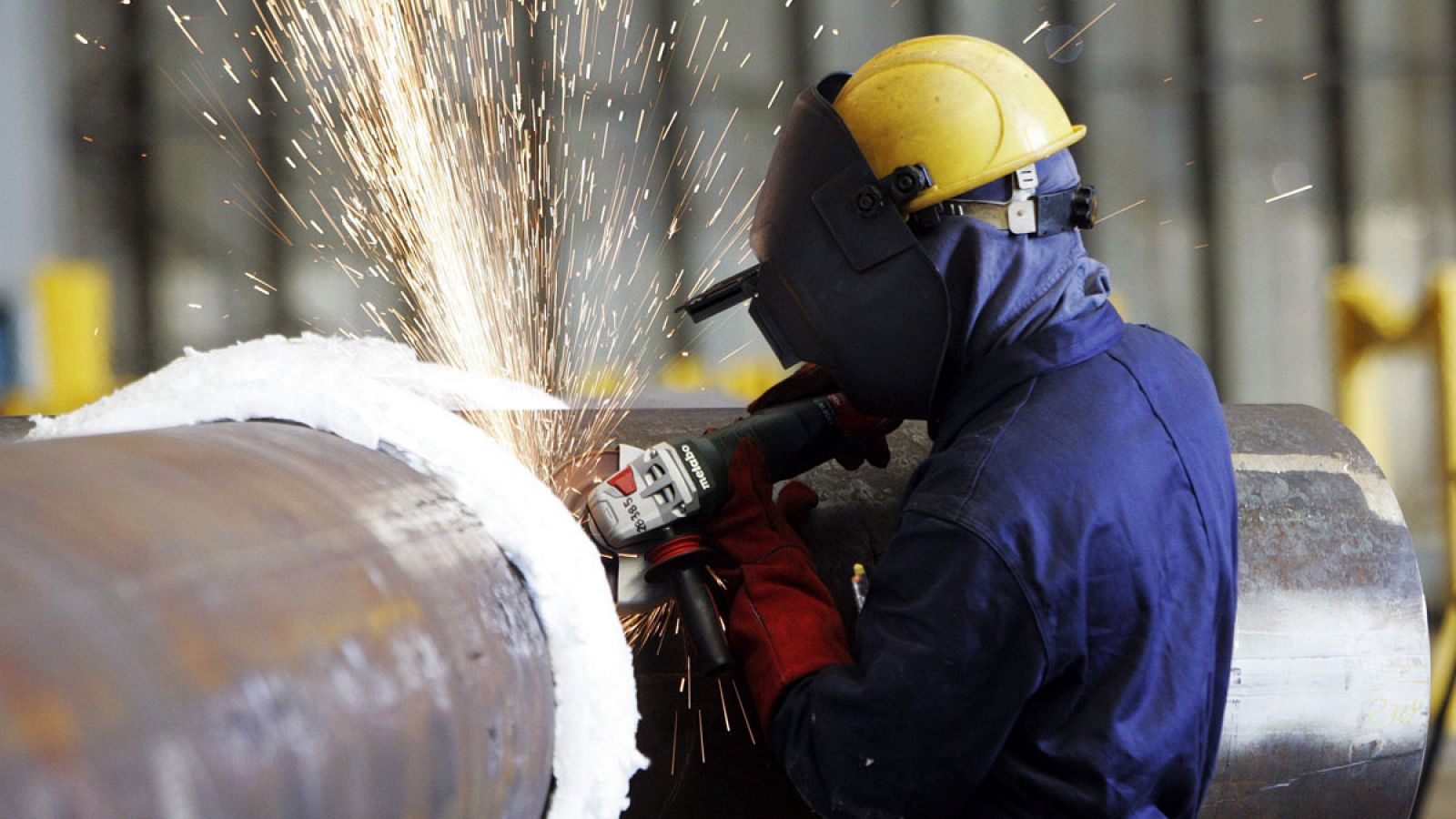 Un trabajador suelda un tubo en un astillero.