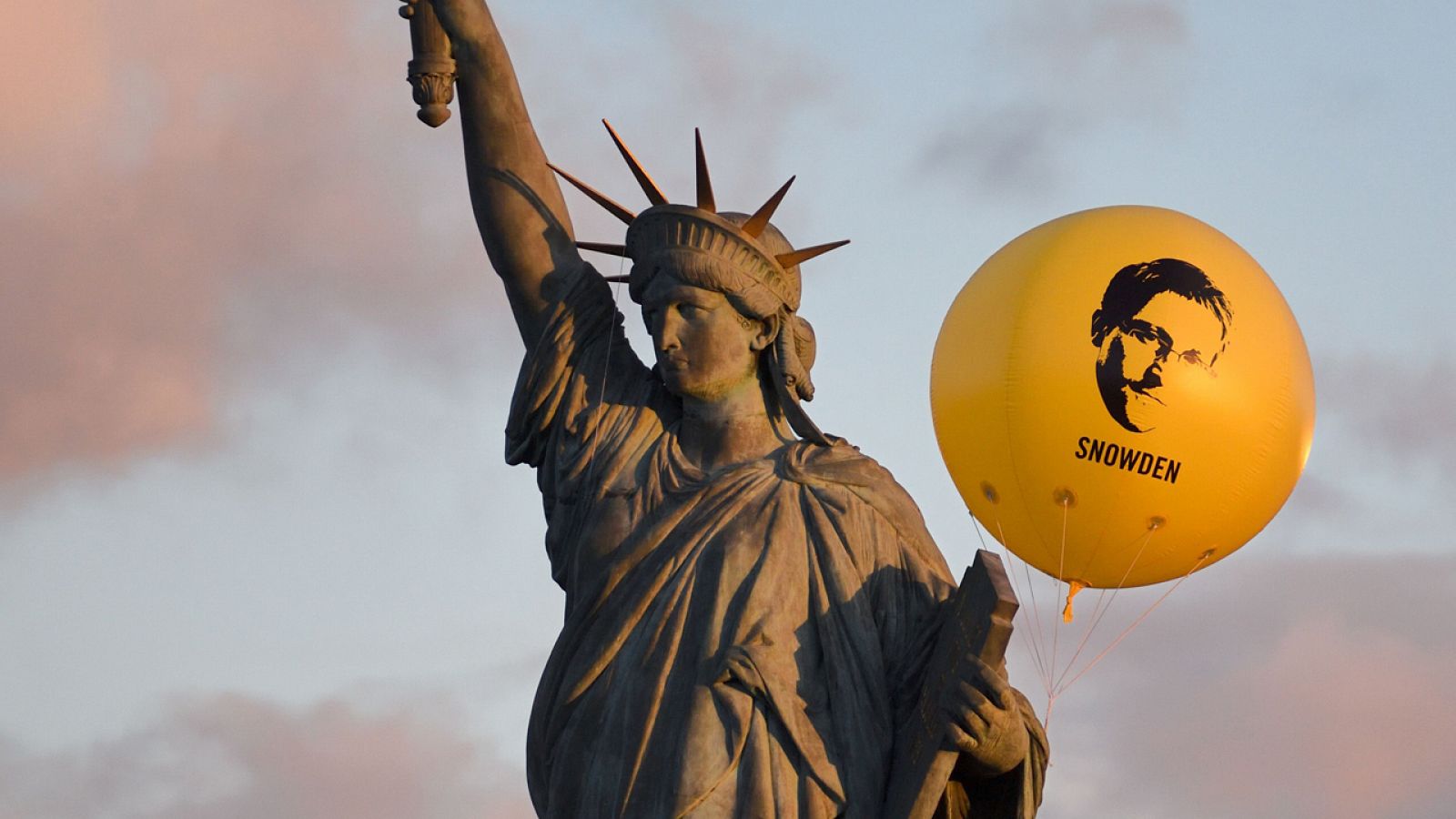 Un globo con la cara de Edward Snowden fotografiado junto a esta réplica de la Estátua de la Libertad en París