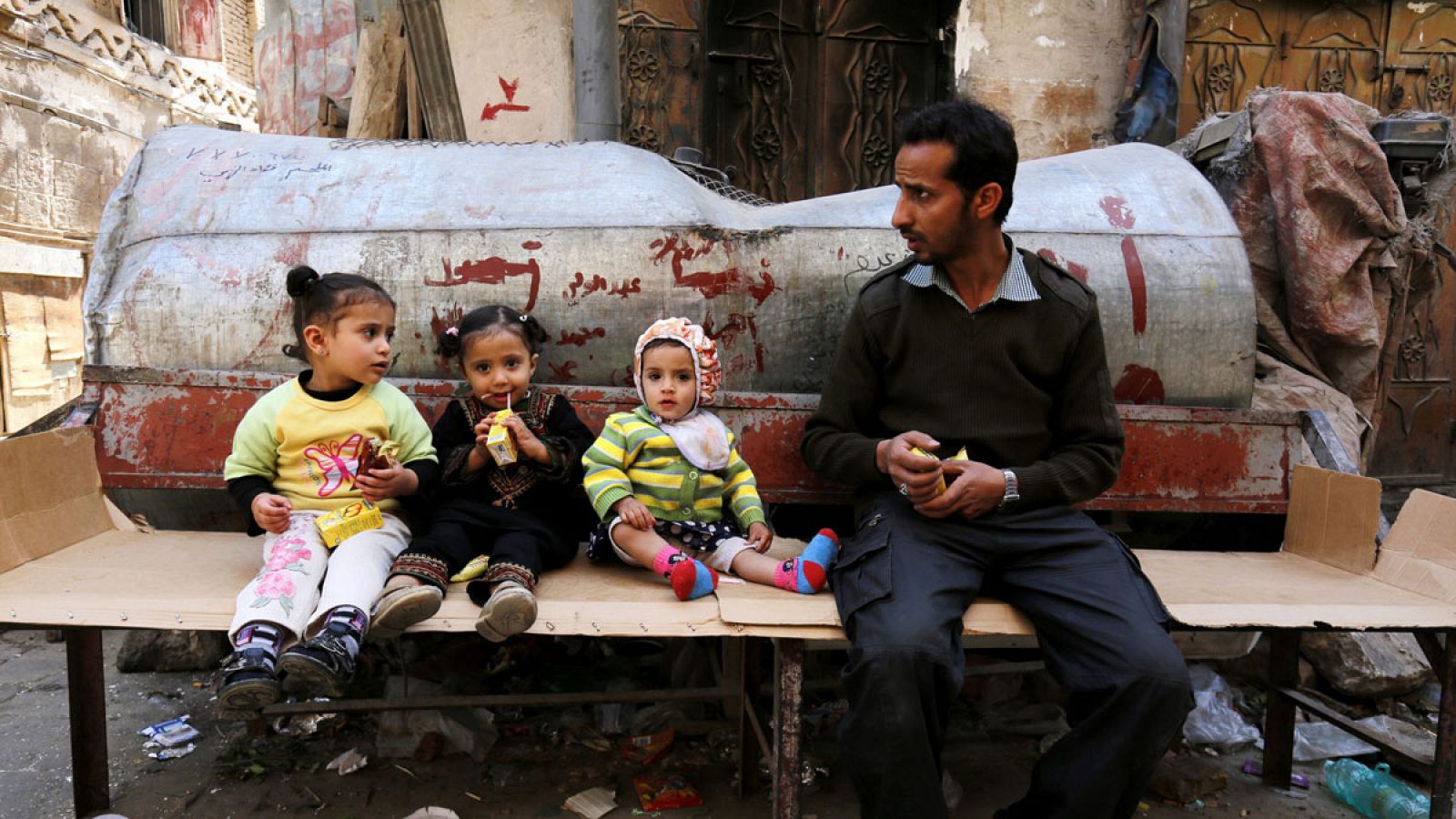 Un yemení se sienta junto a tres niños en Saná, Yemen.