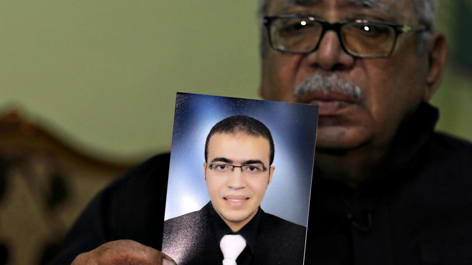El padre del sospechoso del ataque del Louvre, Reda Abdallah el Hamamy, sostiene una fotografía de su hijo en su casa de Daqahliya, en Egipto