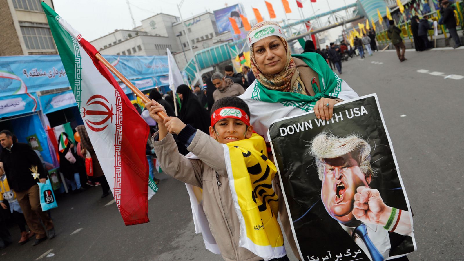 Una mujer iraní participa en la marcha de Teherán con una caricatura de Trump.