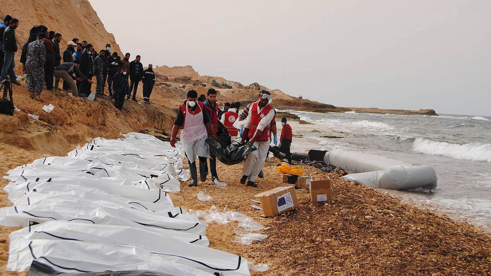 Miembros de la Media Luna Roja de Libia junto a los 74 cuerpos hallados en la playa de Zawiya, en Libia