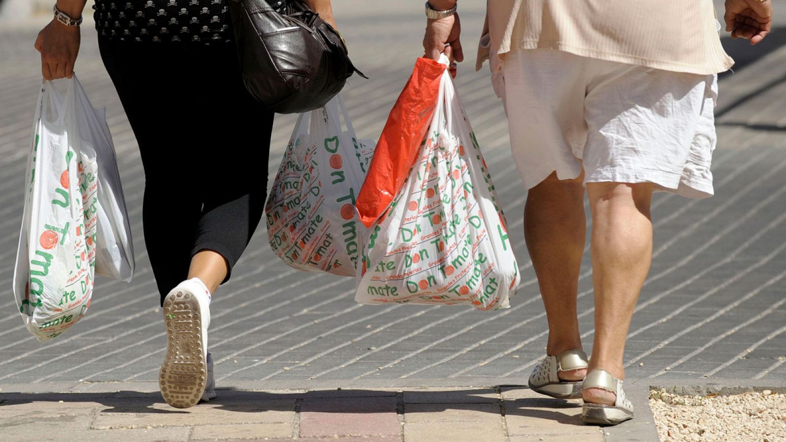 Dos mujeres llevan bolsas de plástico tras realizar unas compras.