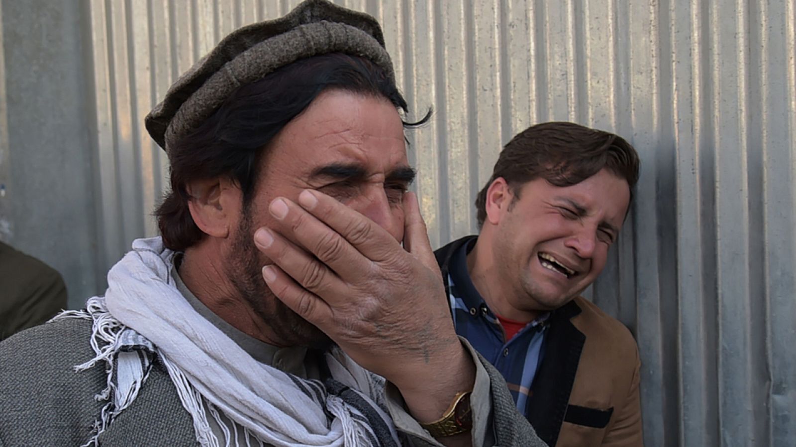 Dos hombres afganos lloran por sus familiares frente a la puerta del principal hospital militar de  Kabul.