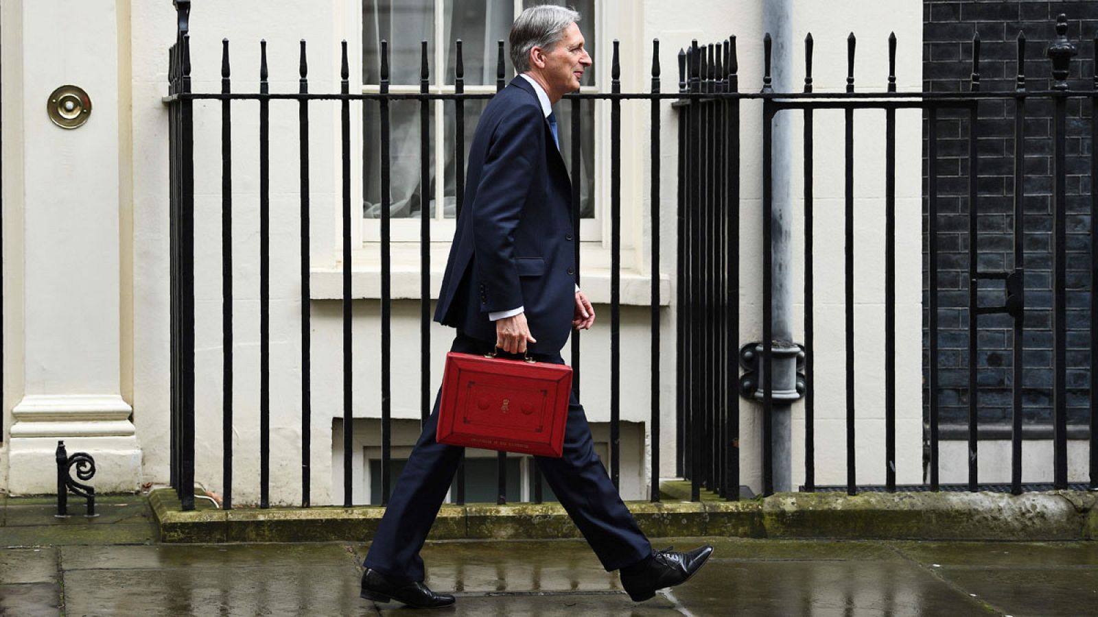 El ministro de finanzas de Reino Unido, David Hammond, camina con el maletín de los Presupuestos hacia el número 11 de Downing Street.
