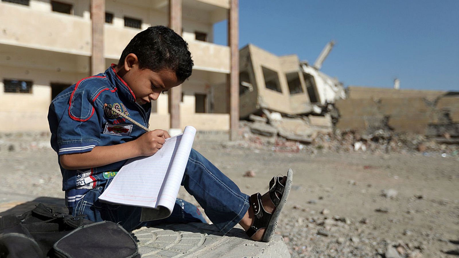 Un niño yemení hace los deberes sobre las ruinas de su escuela bombardea en Taiz.