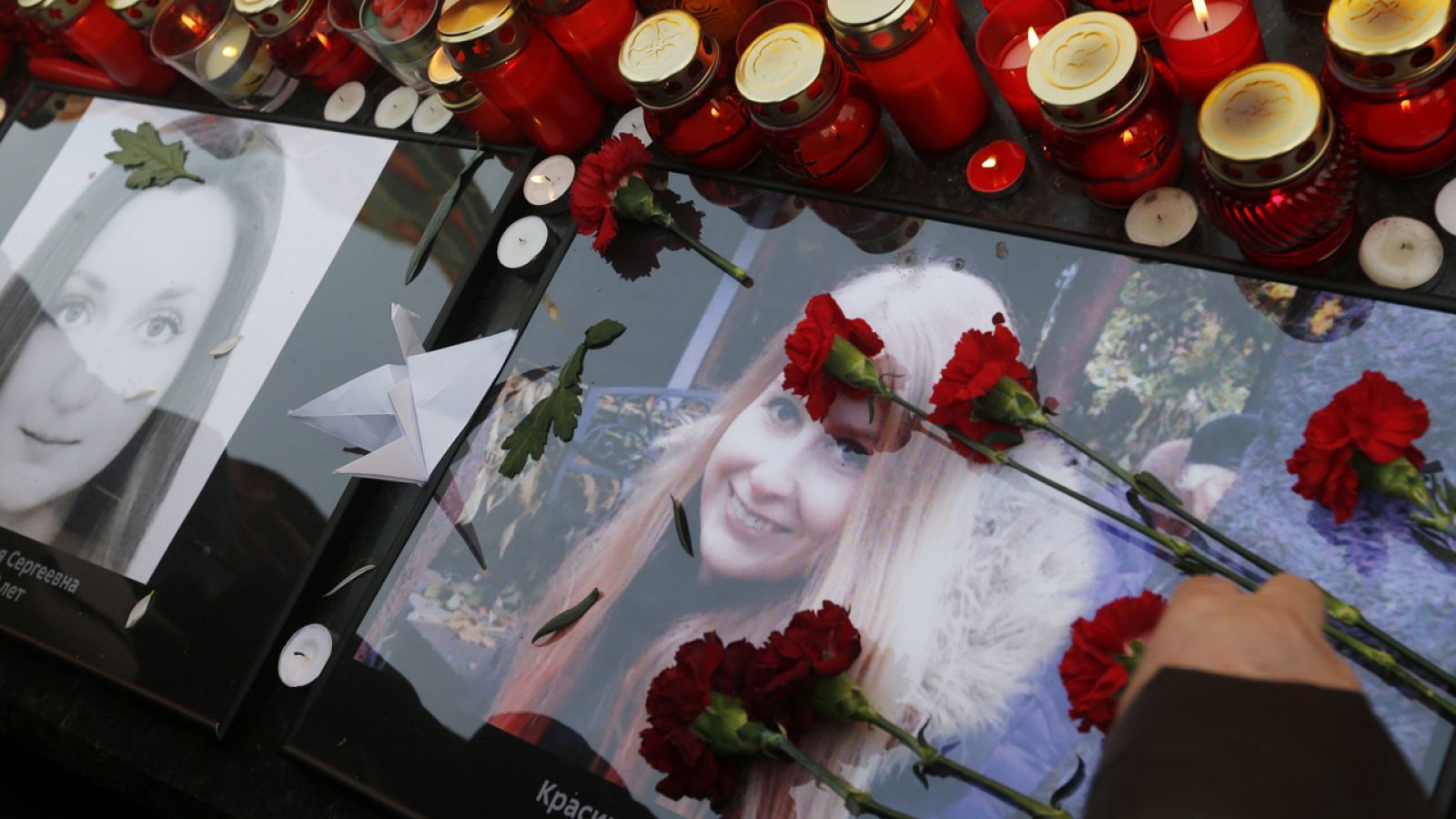 Varias personas depositan flores y velas durante una marcha en memoria de las víctimas del atentado en el metro de San Petersburgo