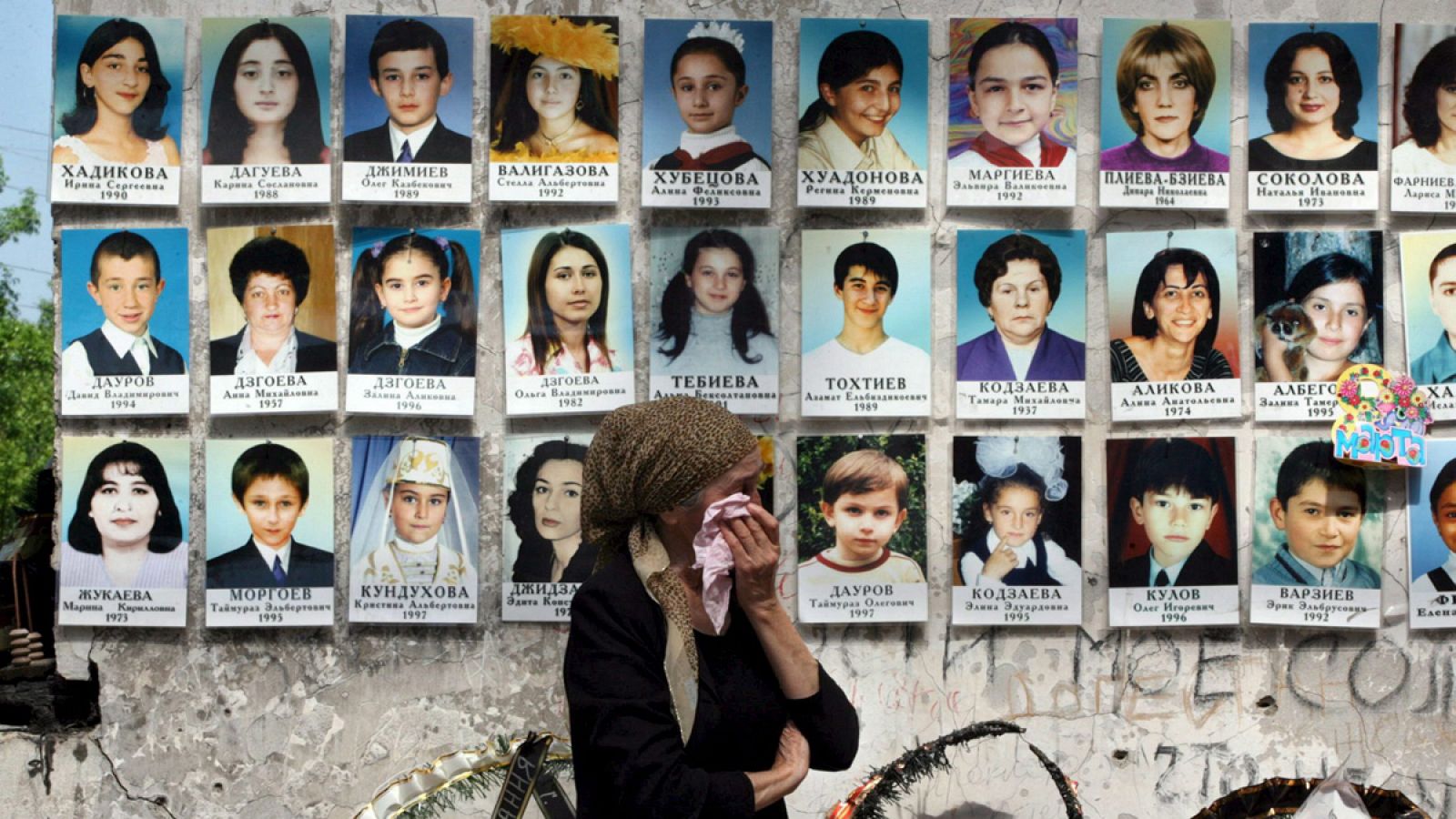 Una mujer llora al pasar por delante de una pared cubierta con los retratos de los fallecidos -entre ellos, muchos niños- en el secuestro de un colegio ocurrido en septiembre de 2004 en Beslán.