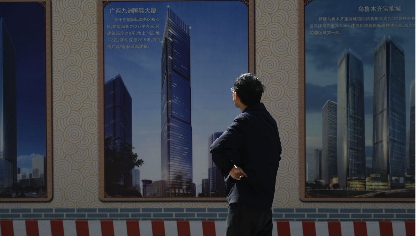 Un hombre contempla el poster de una construcción en Pekín.