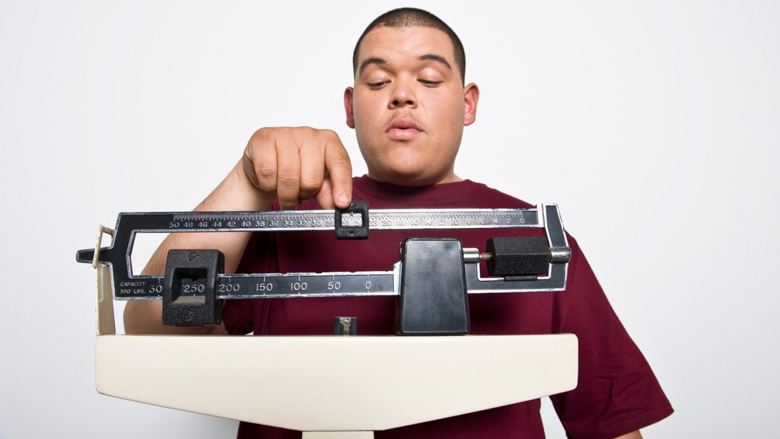 Obesidad - Un hombre joven pesándose en una báscula