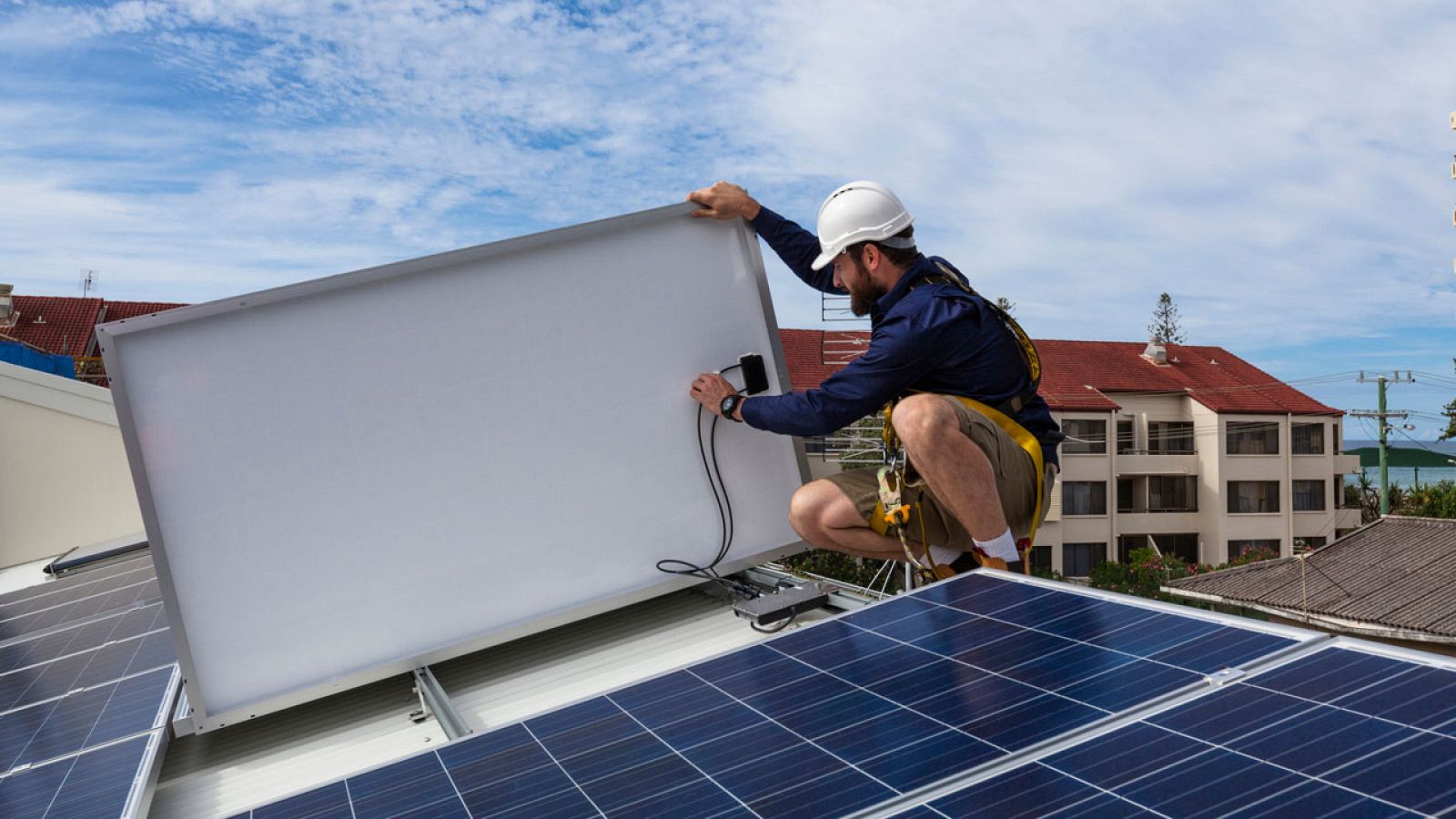 Un operario coloca placas solares en el tejado de un edificio