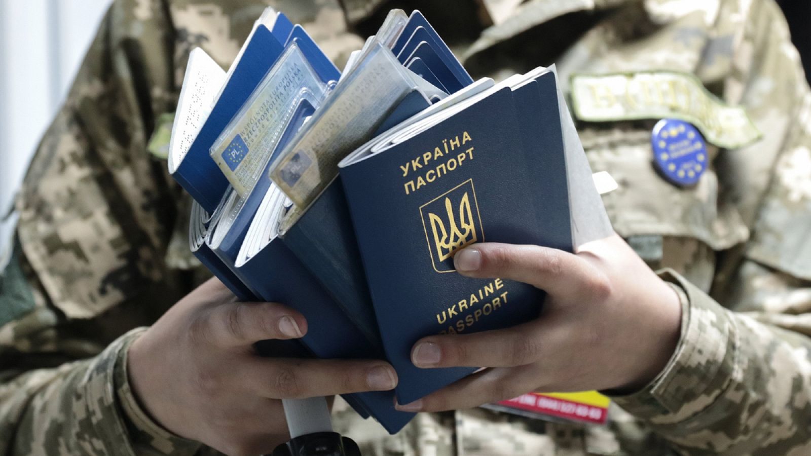 Un policía de fronteras de Ucrania sostiene varios pasaportes.