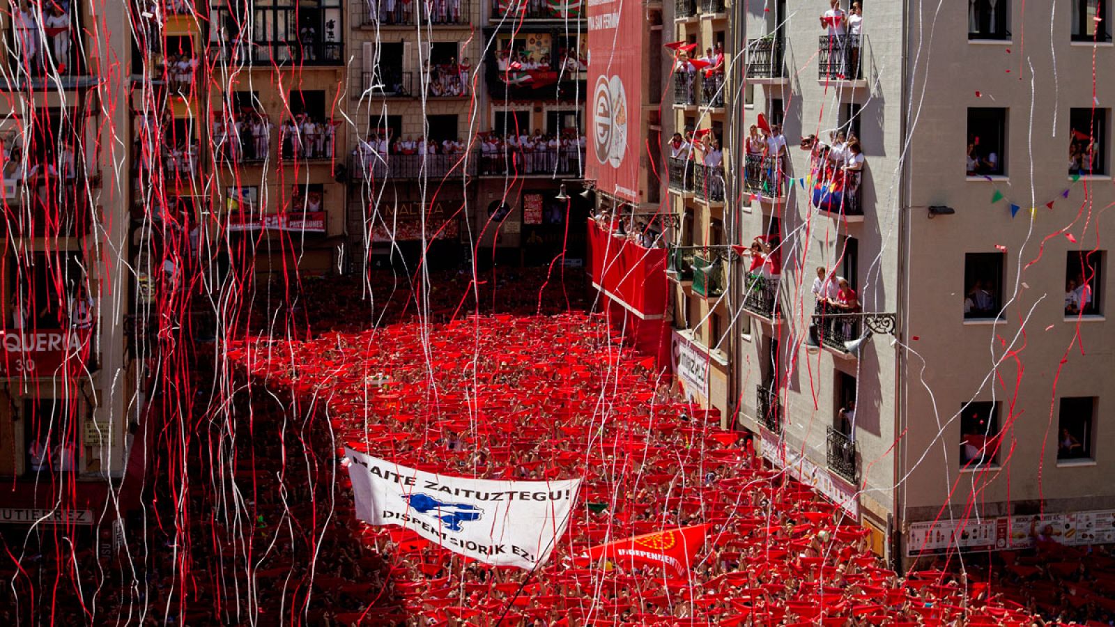 Miles de personas muestran en alto el "pañuelico" rojo en la Plaza del Ayuntamiento de Pamplona durante el chupinazo de 2016