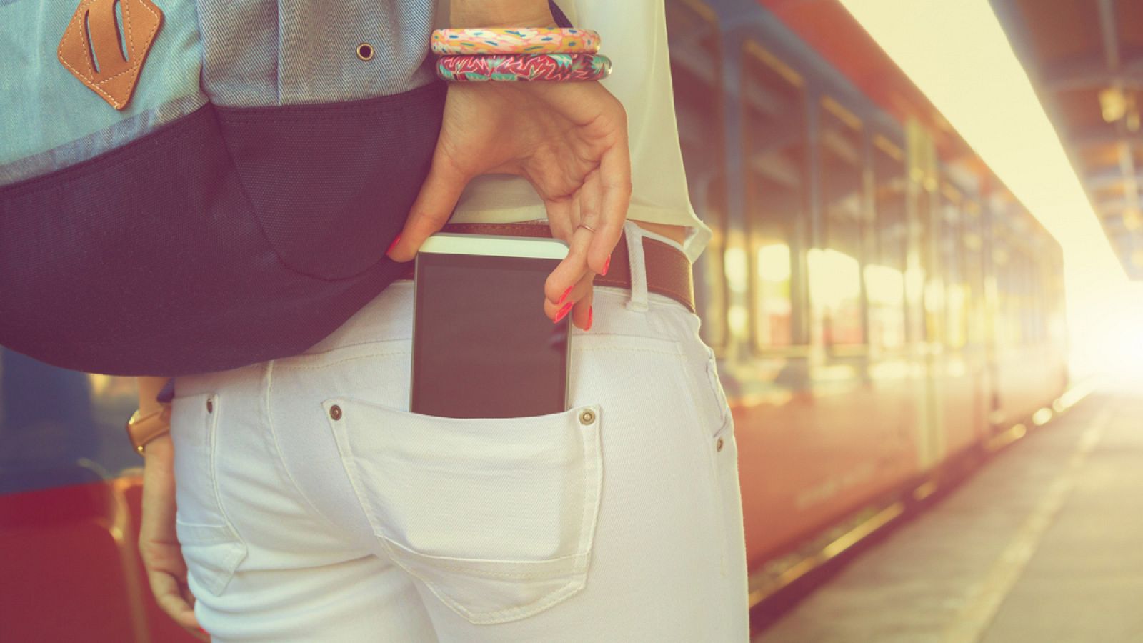 Una joven guarda su teléfono móvil en el bolsillo de su pantalón