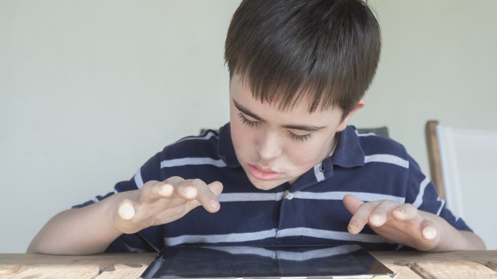 Un niño con Síndrome de Down juega en una tablet.