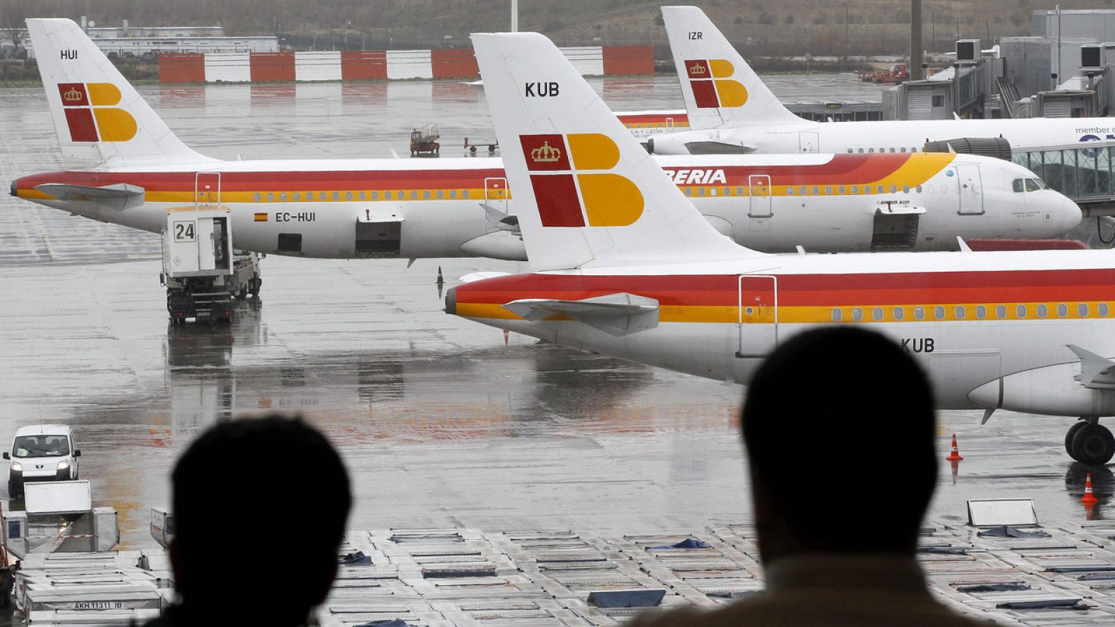 Dos pasajeros observan aviones de Iberia en Barajas en una imagen de archivo