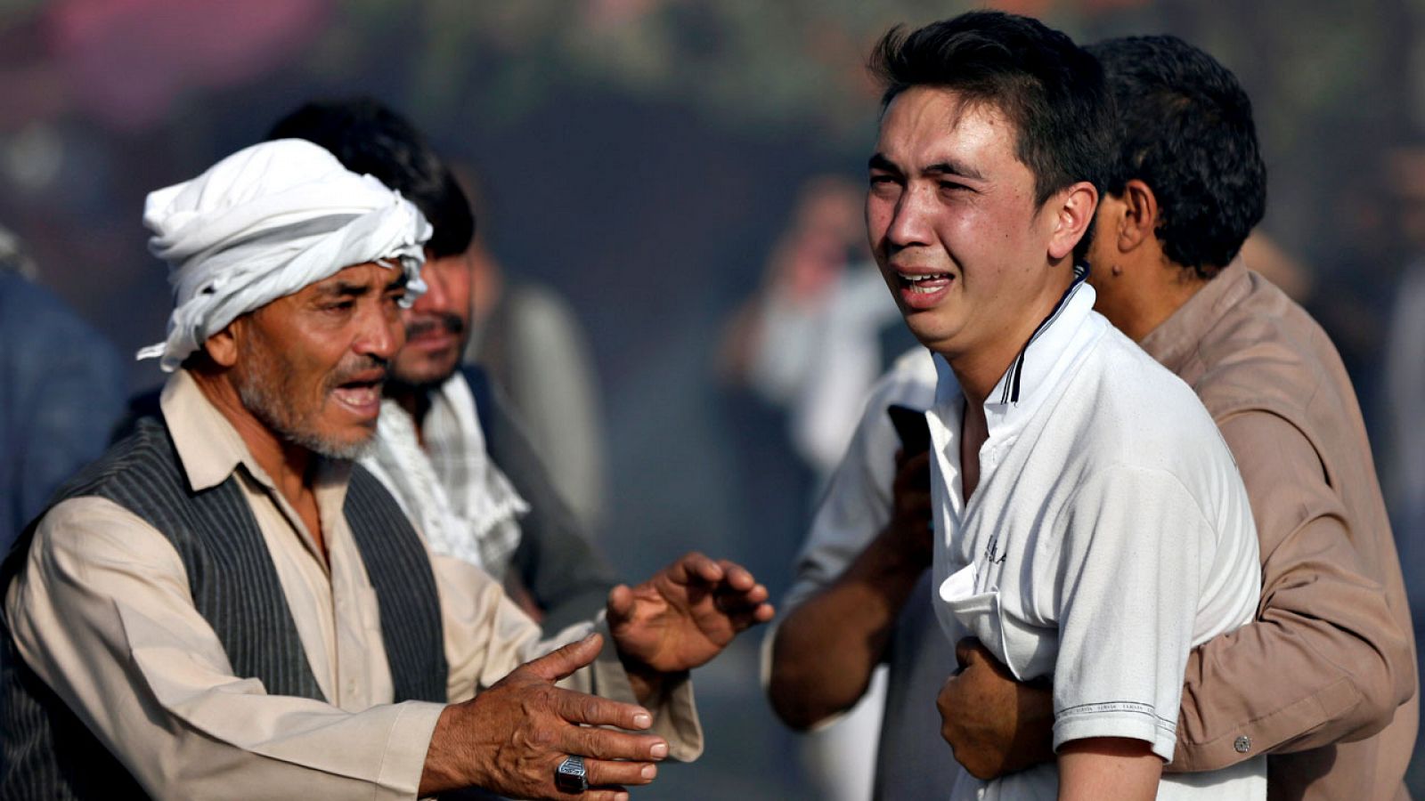 Varios hombres tratan de consolar a un joven tras conocer la muerte de sus parientes en la mezquita atacada en Kabul