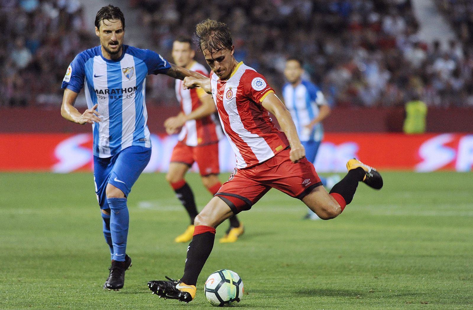 El defensa del Girona Marc Muniesa (d) disputa un balón con el jugador del Málaga Zdravko Kuzmanovic.
