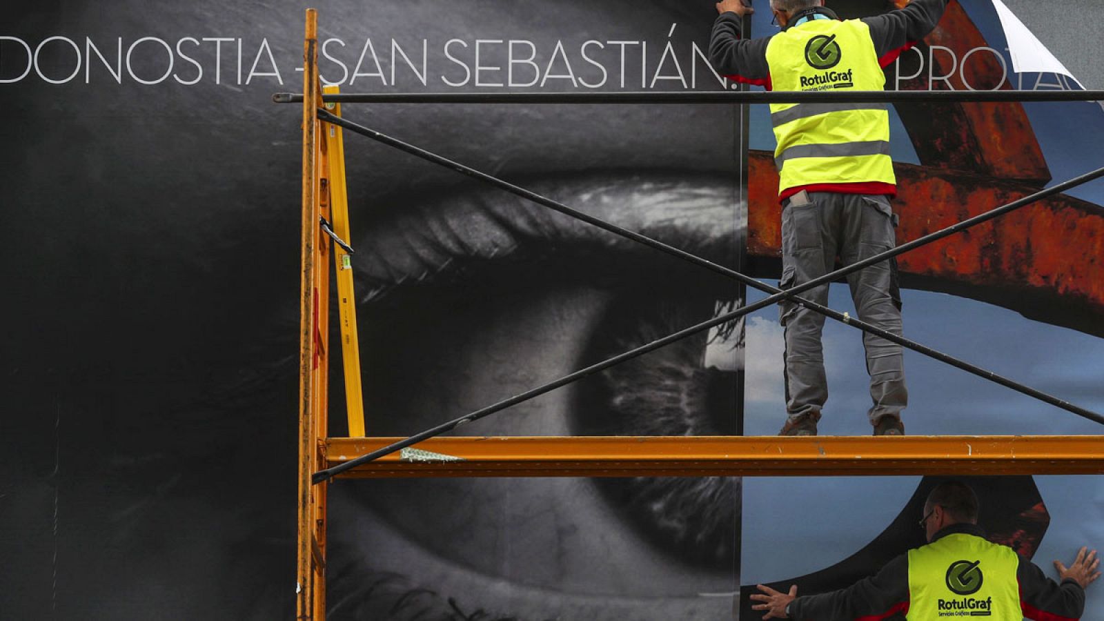 Operarios colocan uno de los carteles del Festival Internacional de Cine de San Sebastián.