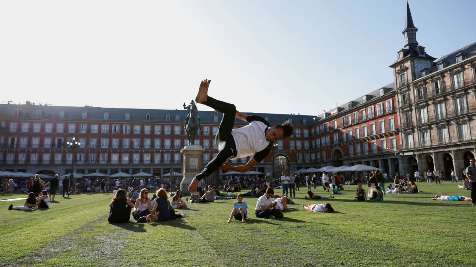 Turistas disfrutan de la hierba provisional en la Plaza Mayor de Madrid