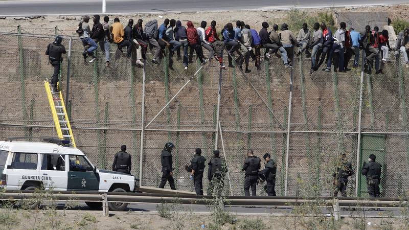 Varios inmigrantes encaramados a la valla de Melilla el 13 de agosto de 2014