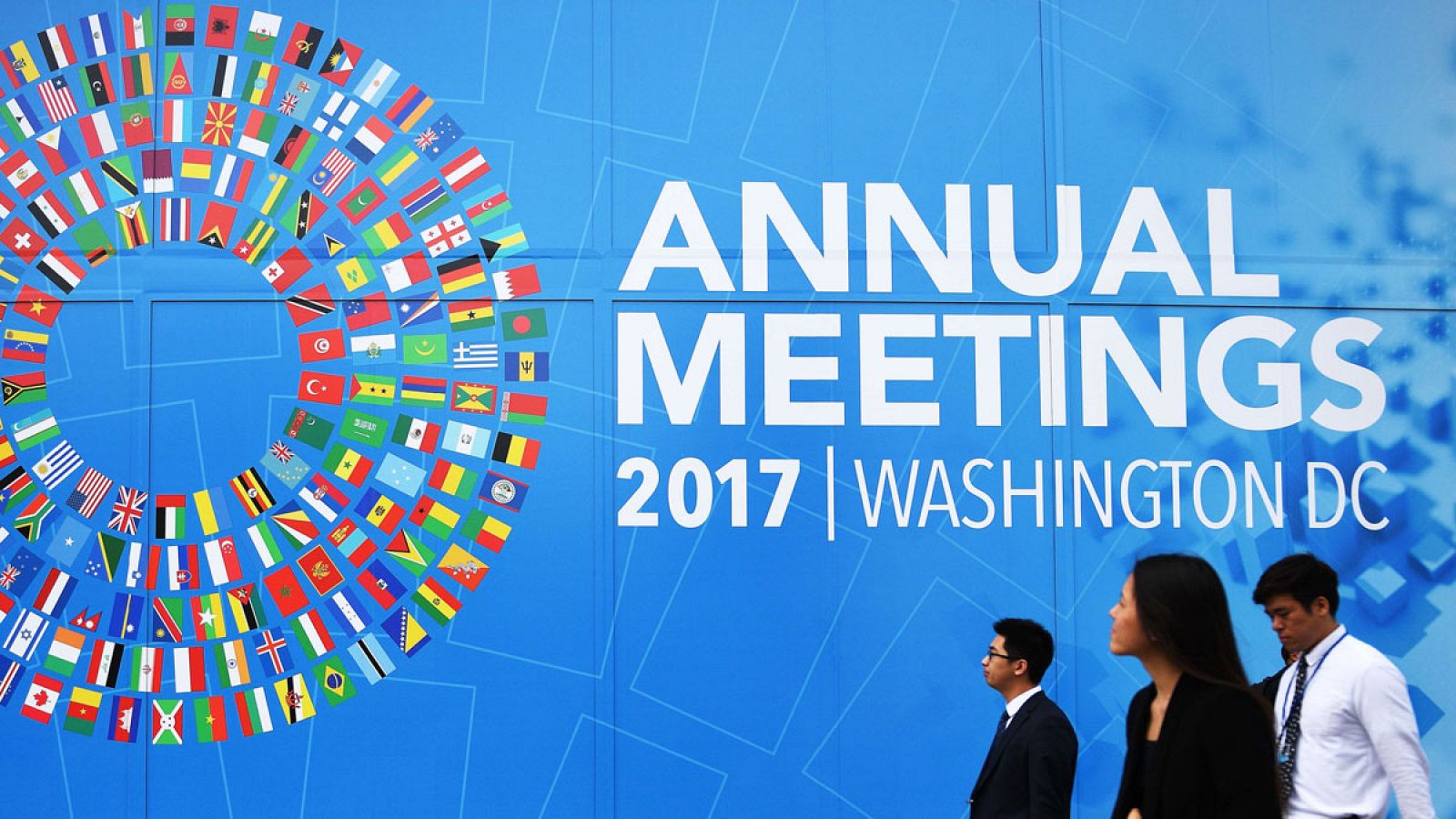 Varios viandantes miran los anuncios de la reunión anual del FMI y el Banco Mundial