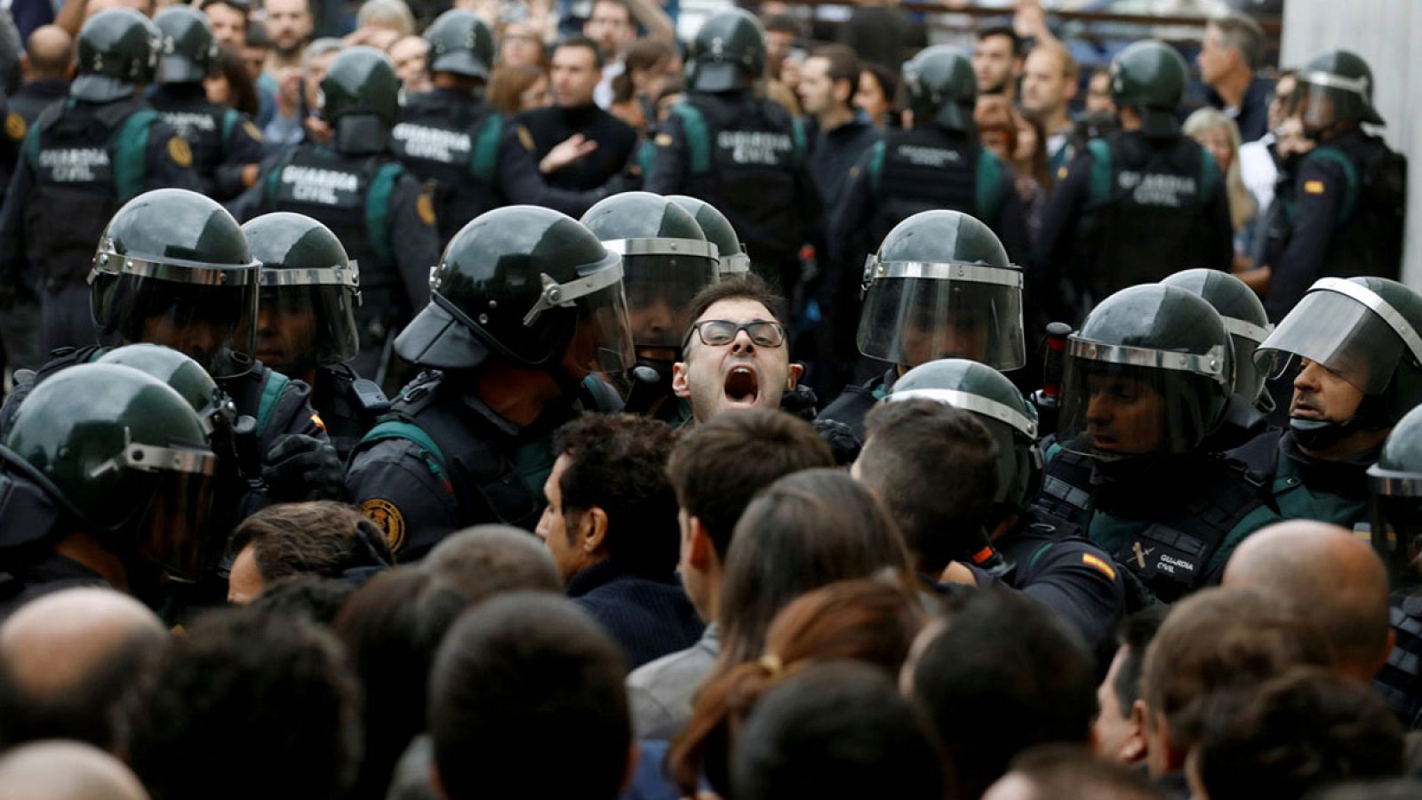 Agentes de Guardia Civil forman un cordón para contener a numerosas personas a las afueras de un local electoral