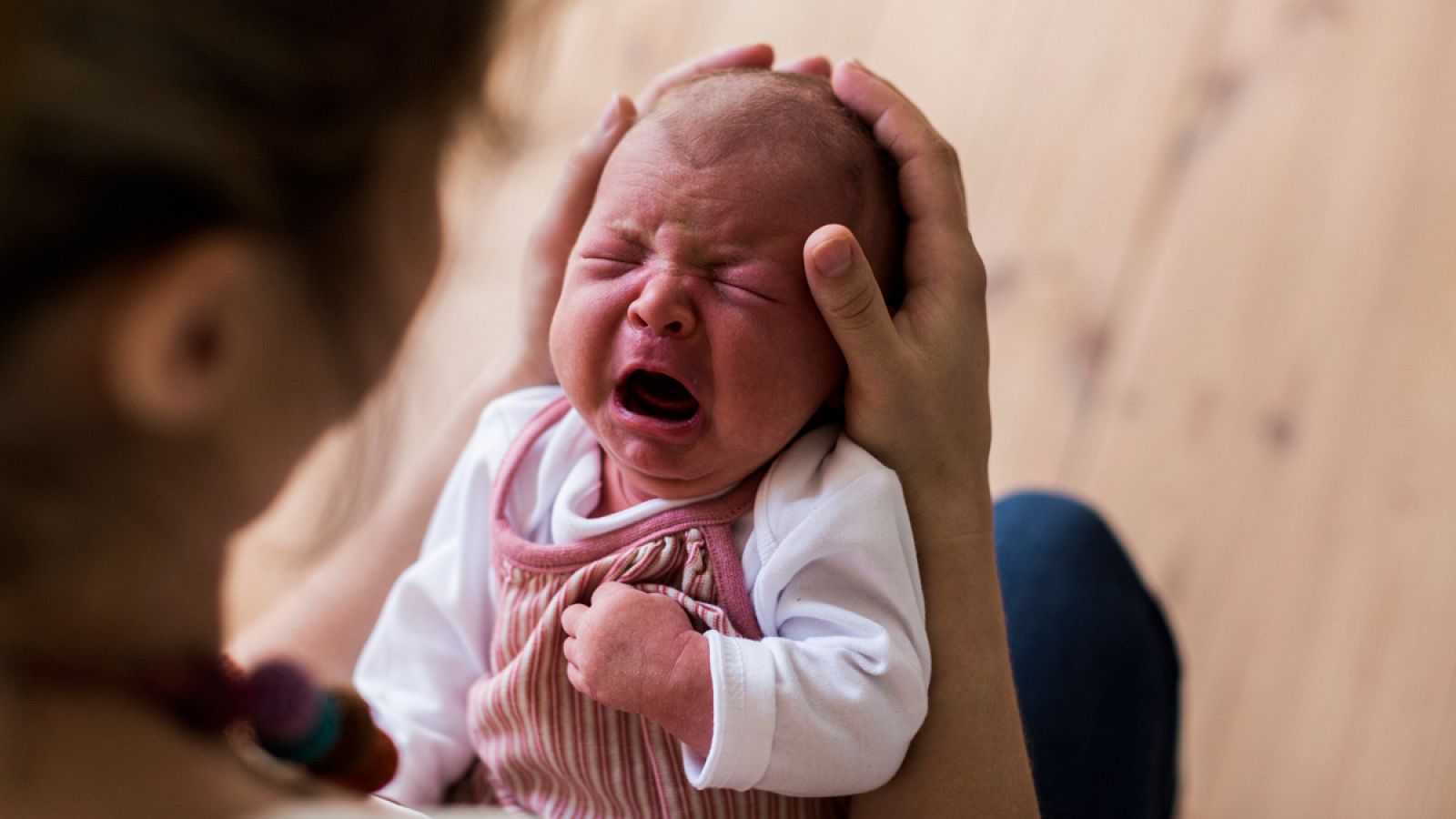 Madre sostiene a un bebé llorando
