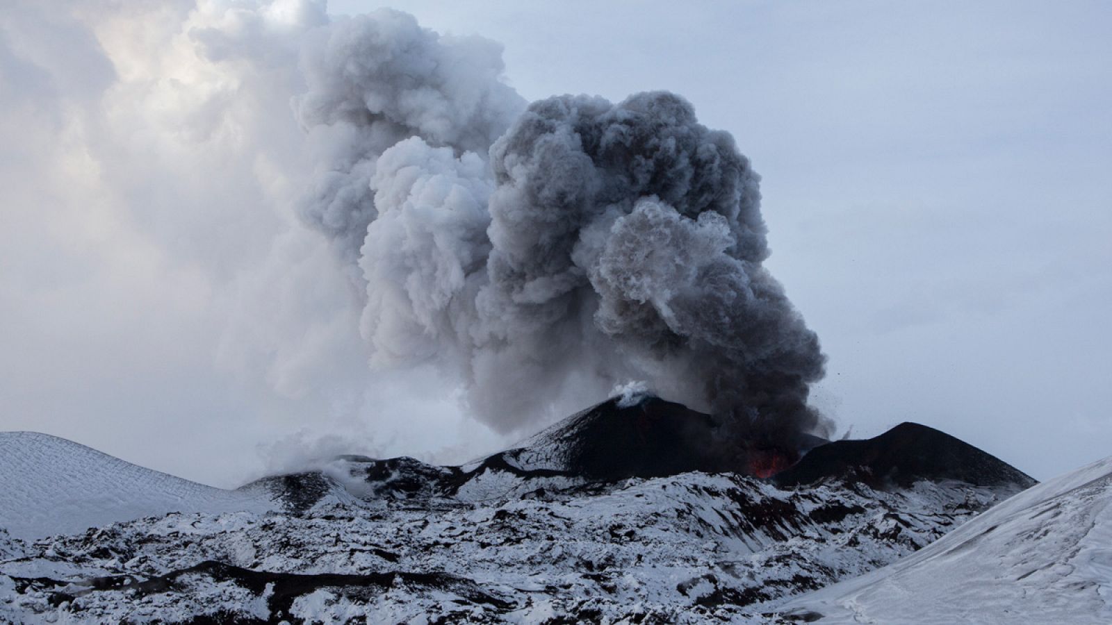 Un volcán en erupción arroja al cielo una nube de cenizas.