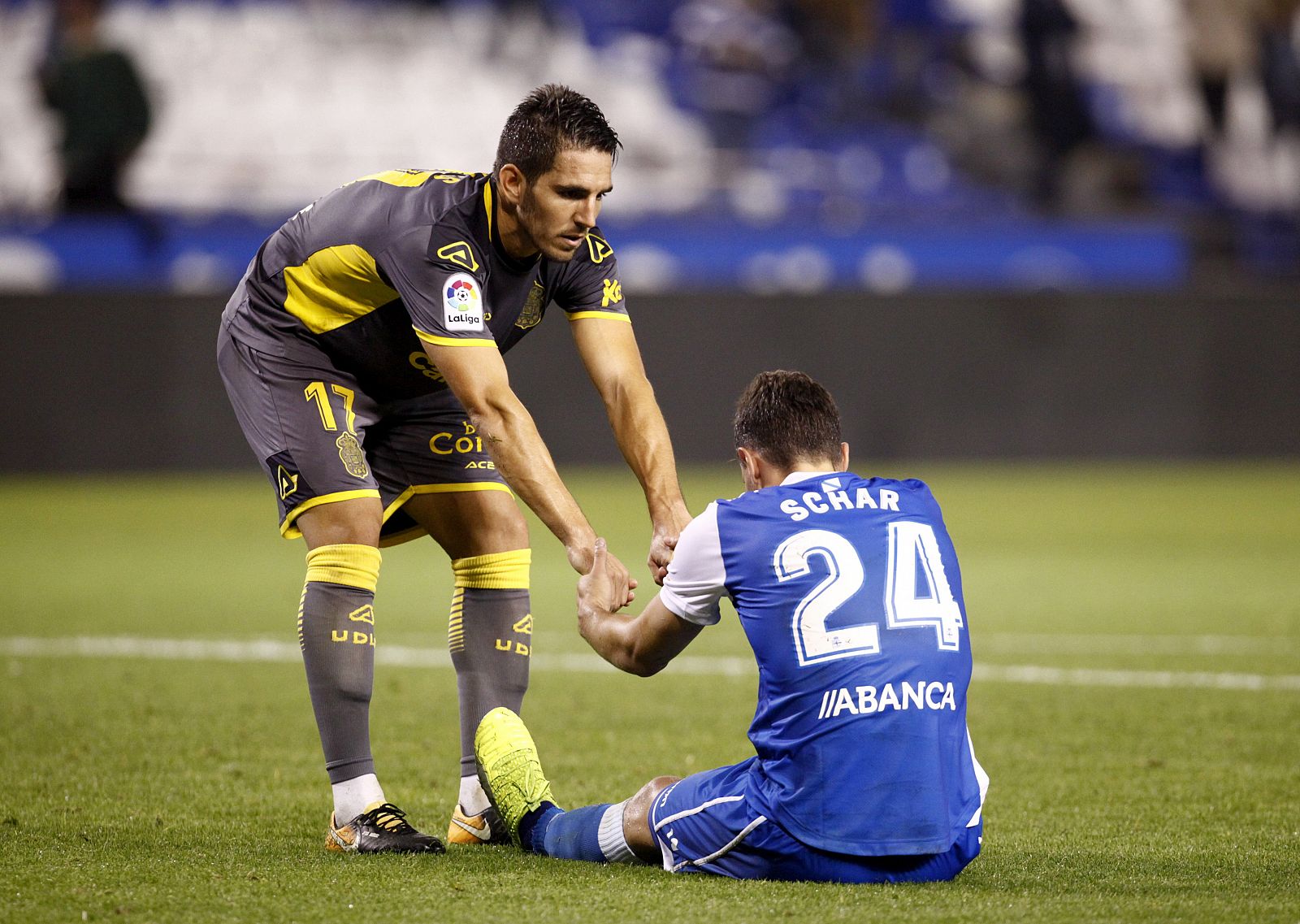 El defensa de la UD Las Palmas Bigas (i) ayuda a levantarse al suizo Fabian Schär, del Deportivo, al finalizar el partido de Copa.