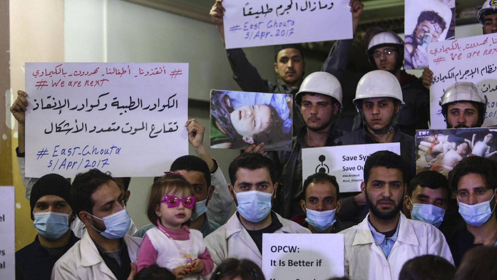 Voluntarios y personal de servicios de primeros auxilios sirios muestran pancartas e imágenes de las víctimas del ataque químico de Jan Shijún, durante una concentración para mostrar solidaridad con los fallecidos en Douma (Siria) el 5 de abril de 2017.