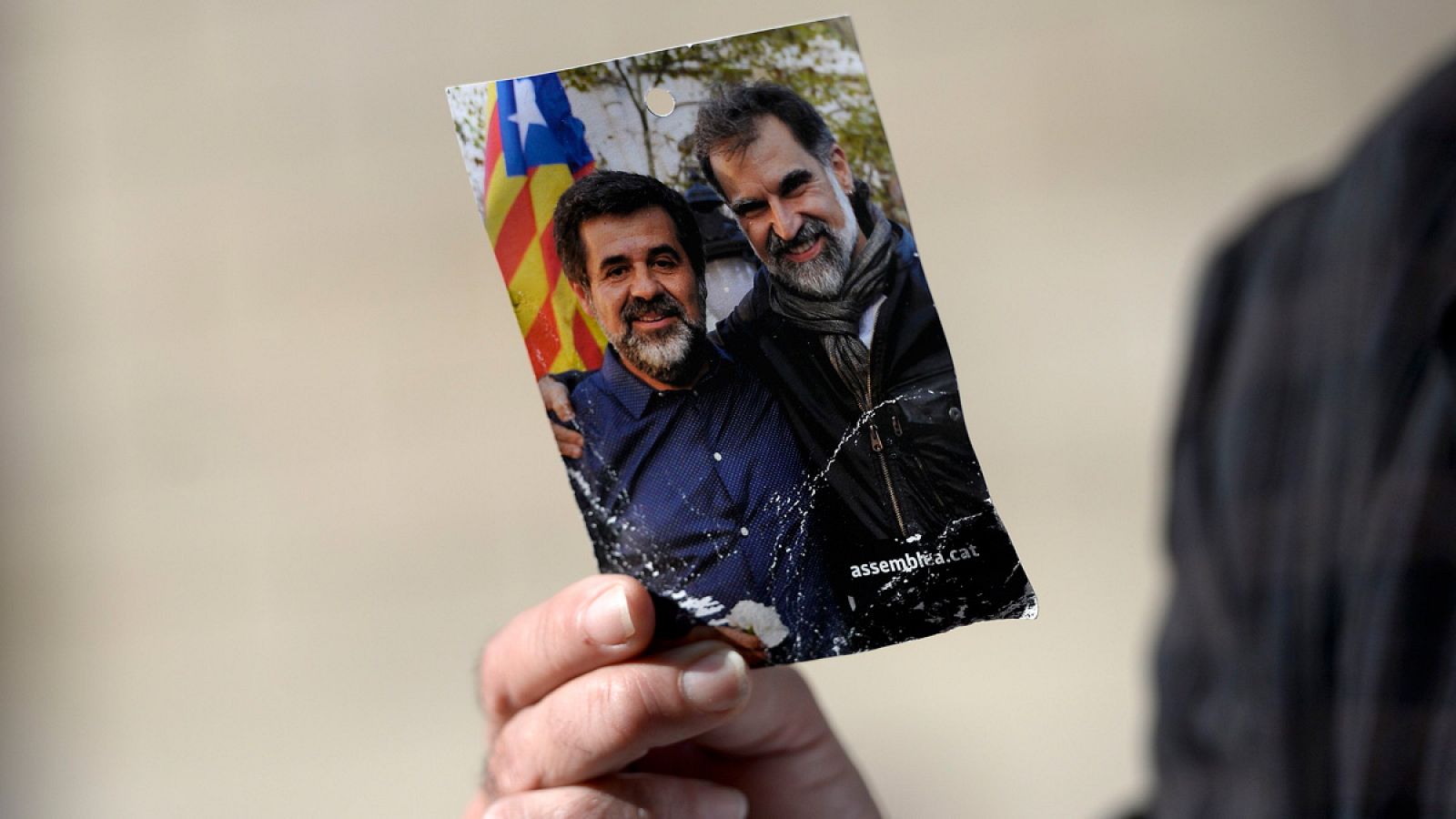Un manifestante independentista muestra una foto de Jordi Sànchez y Jordi Cuixart