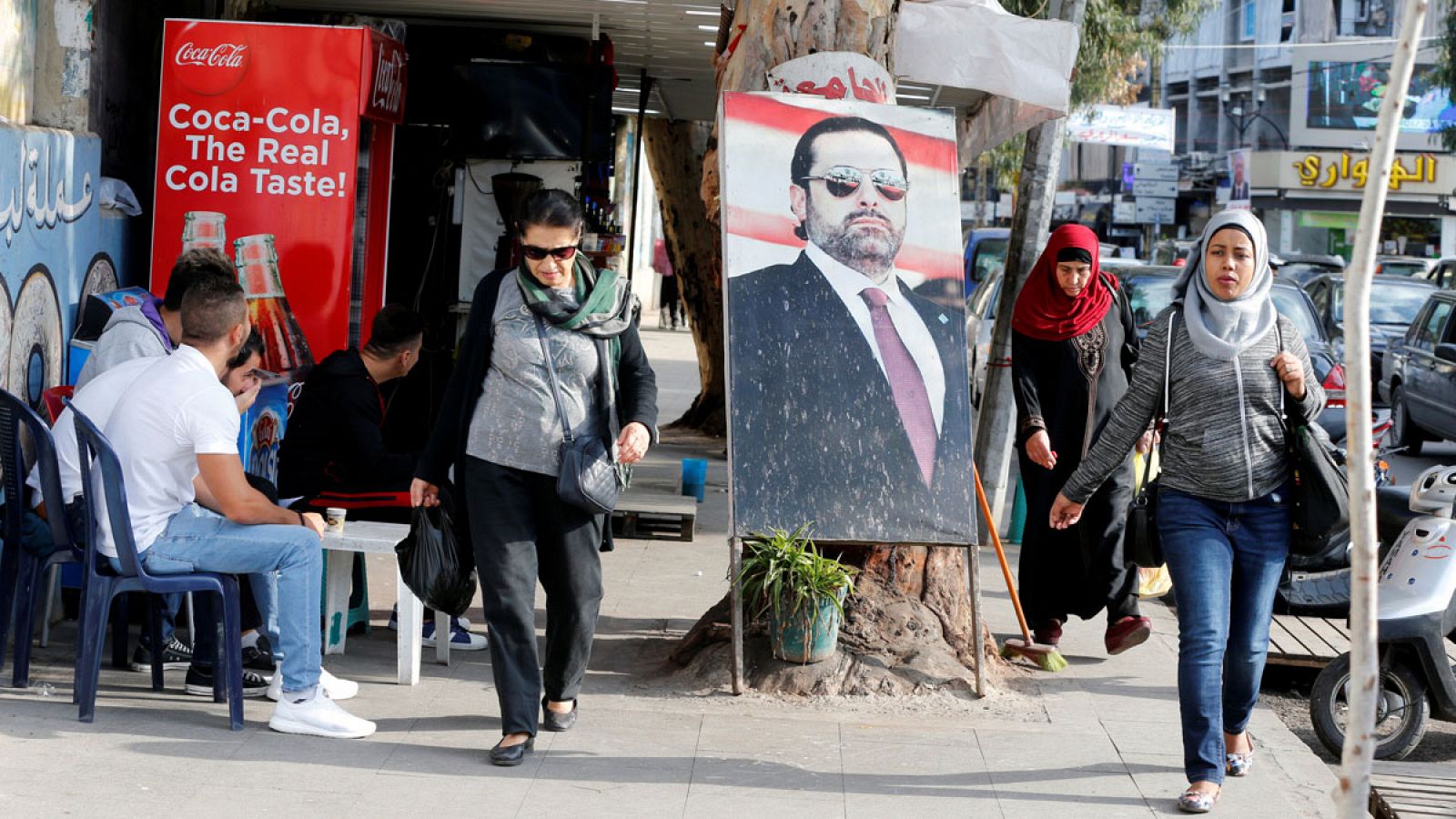 Gente paseando por una calle de Beirut en la que se ve un cartel con la imagen del primer ministro libanés, Saad Hariri.