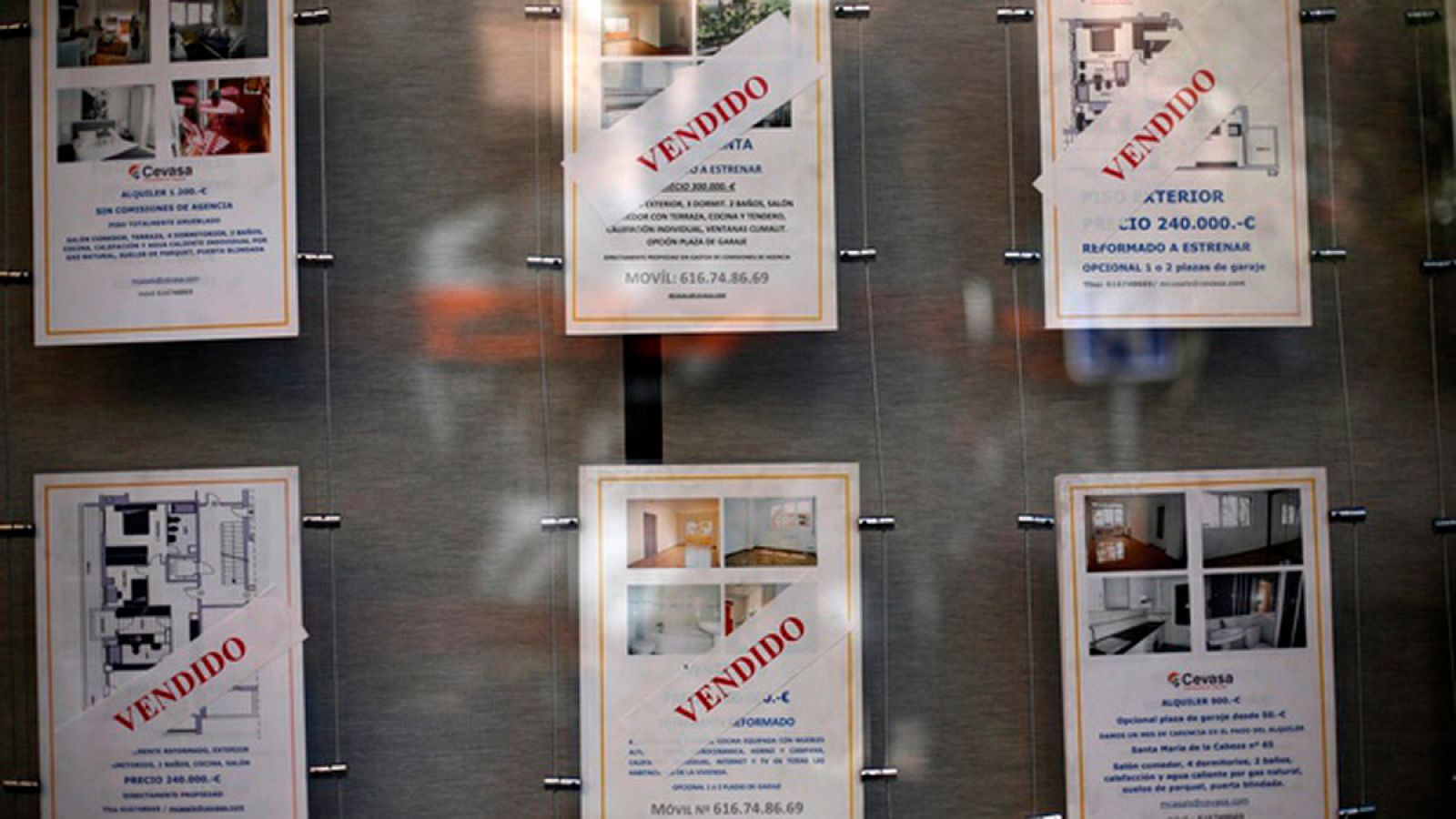 Carteles de viviendas en venta en el escaparate de una inmobiliaria en Madrid