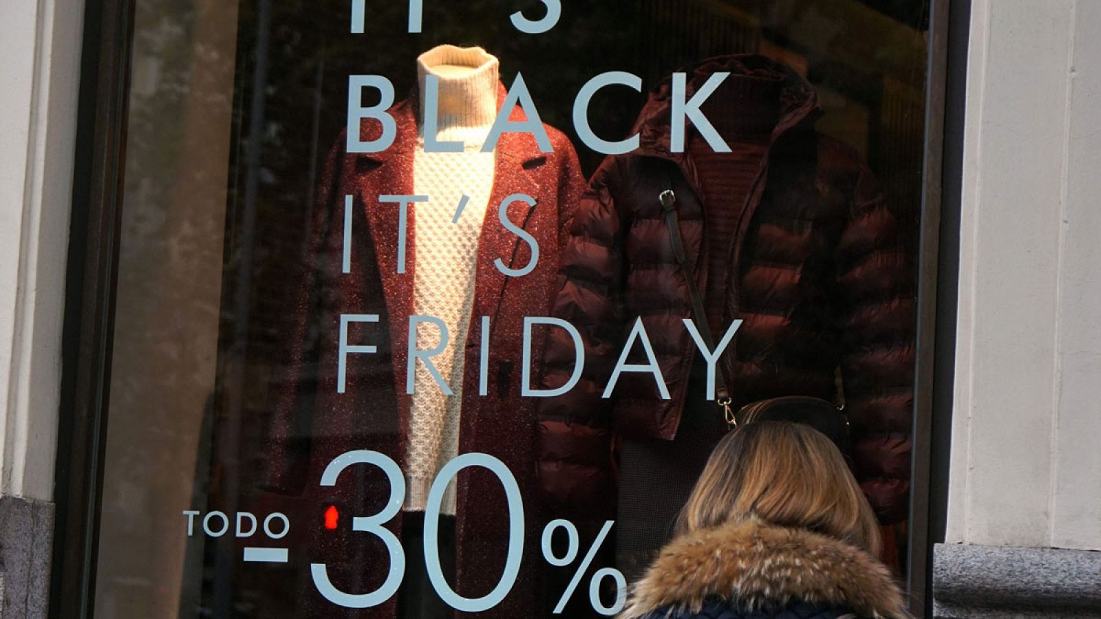 Una transeúnte observa un escaparate con rebajas del Black Friday en una tienda de Madrid