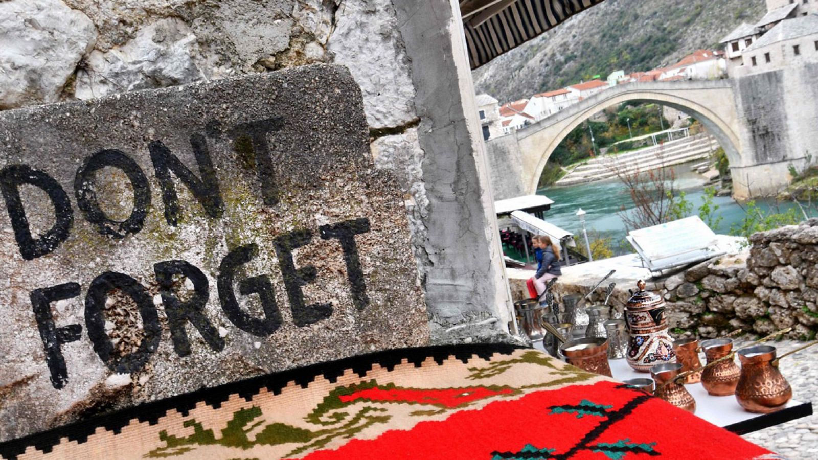 Un cartel en la ciudad bosnia de Mostar con la frase en inglés "No olvidar". Al fondo, el Puente Viejo de la ciudad, destruido por los croatas durante la guerra civil y reconstruido por fuerzas españolas.