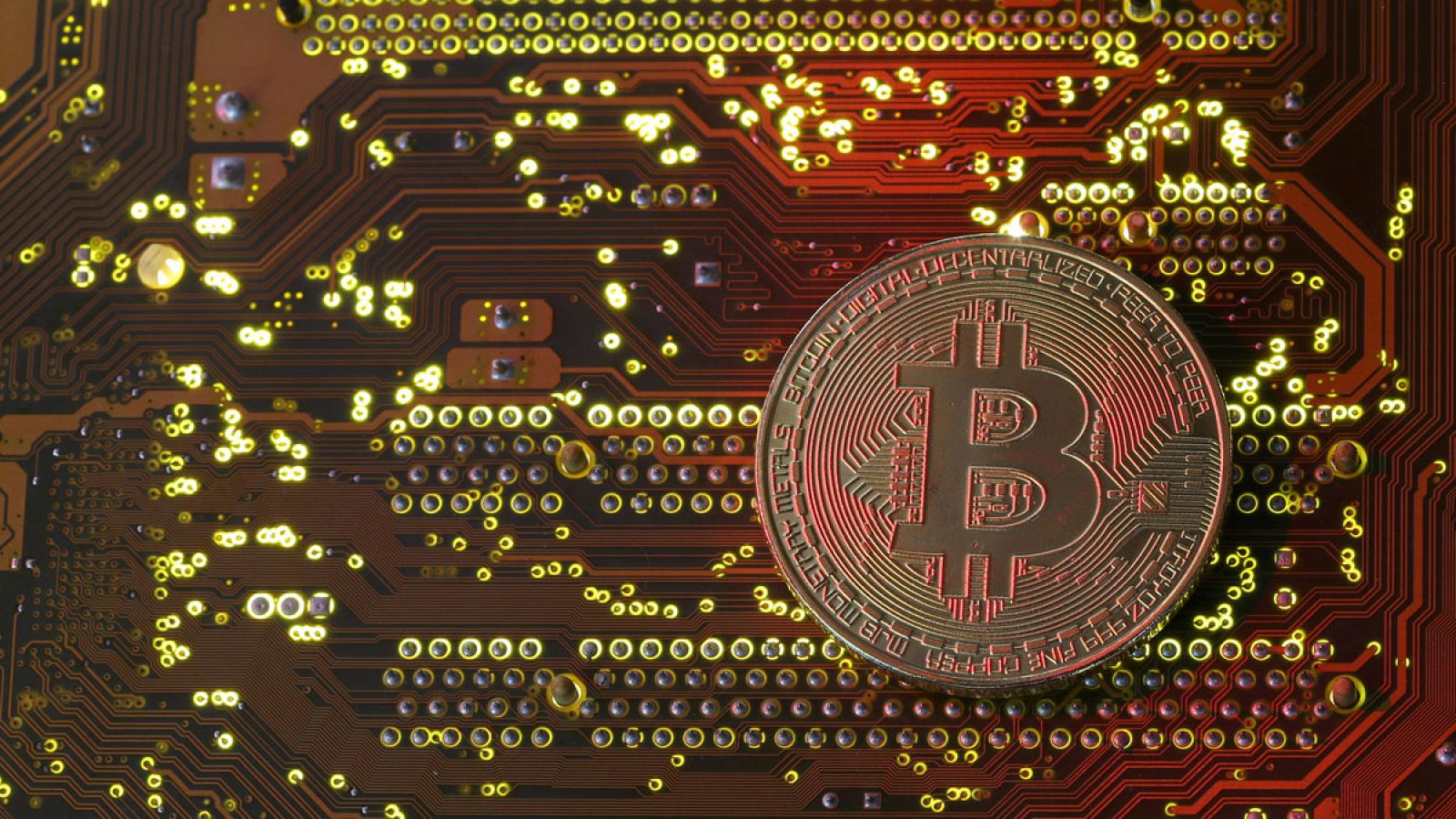 Una pieza de bitcoin delante de una placa base de un ordenador