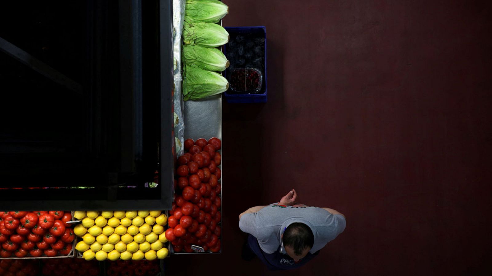 Un frutero espera que lleguen clientes junto a su puesto en un mercado de Madrid