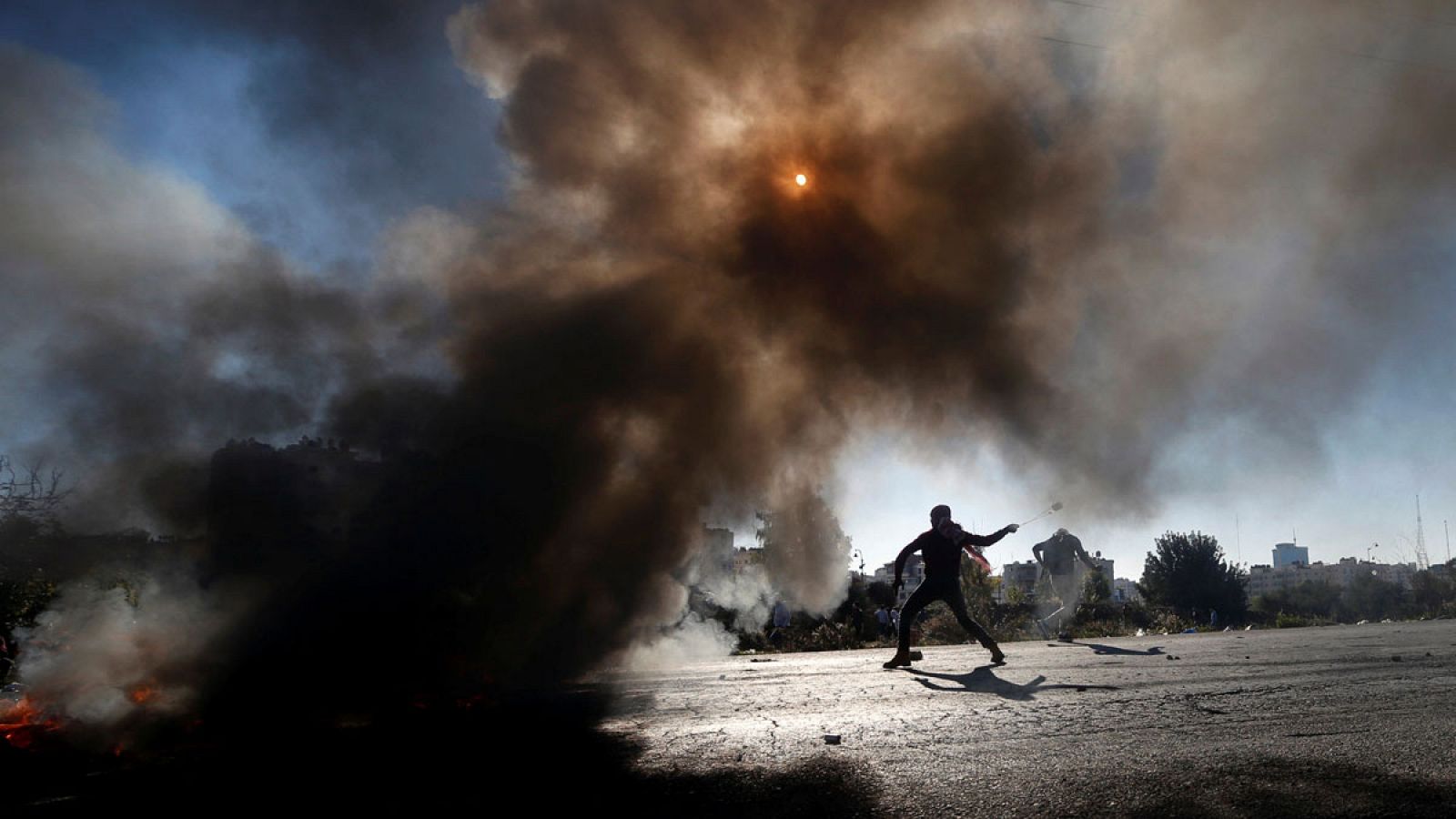 Un palestino arroja piedras con una honda contra las tropas israelíes en el asentamiento judío de Beit El