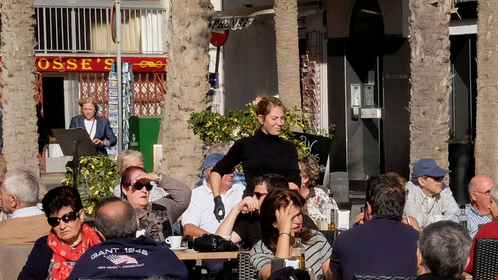 Una camarera sirve mesas en una terraza en Benidorm